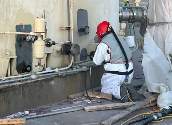 Worker in protective clothing beside tank fittings at the GSI project